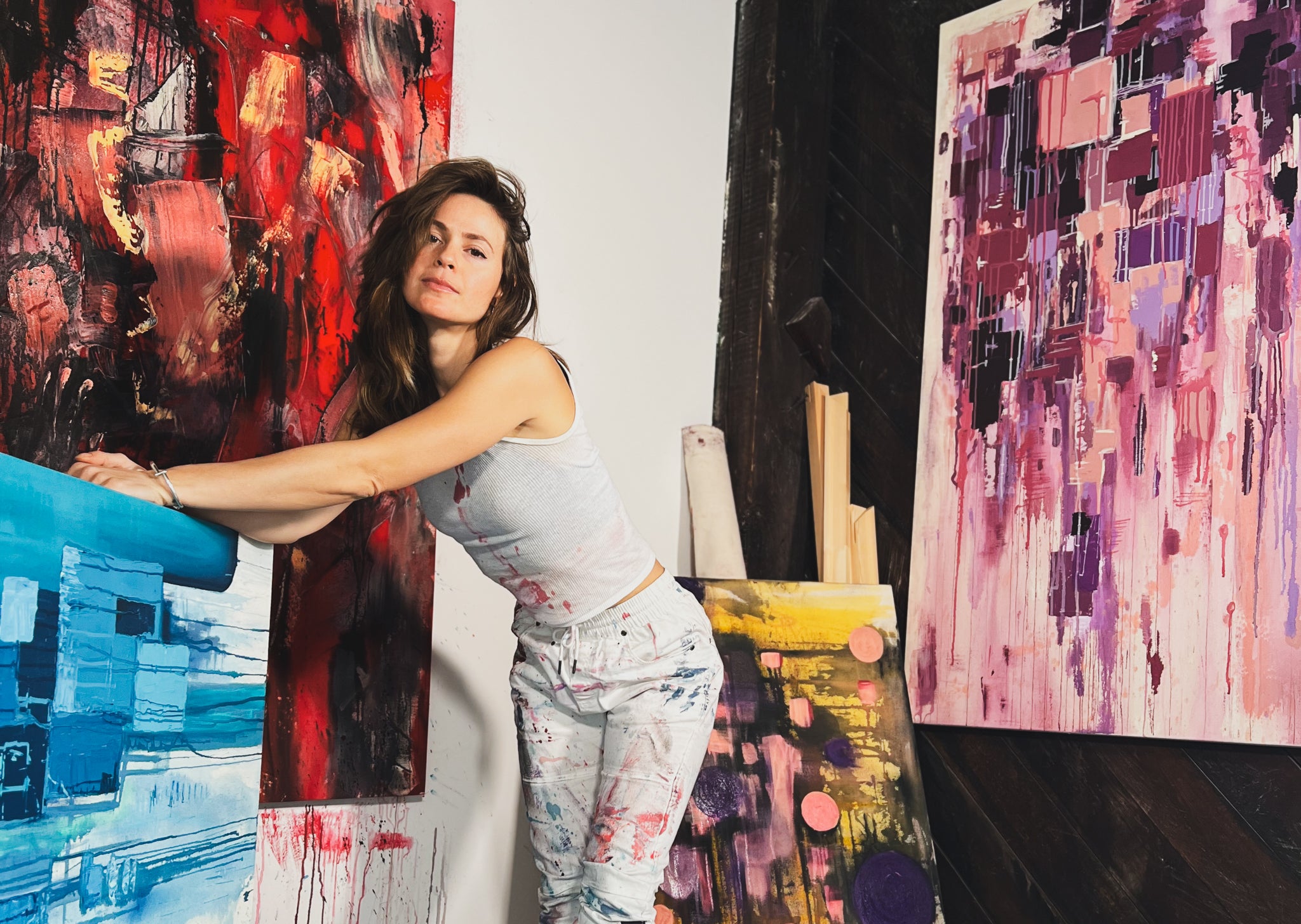 Artist JakiMac in her studio in Nashville TN with multiple colorful abstract painting artworks. 